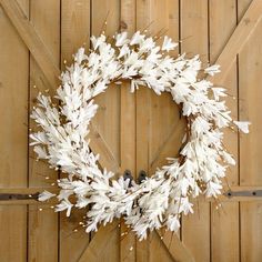 a white wreath hanging on the side of a wooden door