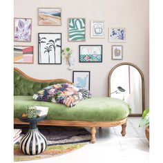 a green couch sitting in front of a wall with pictures on it and a mirror