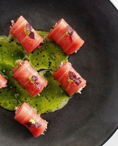 a black plate topped with slices of sushi