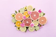 a bunch of cut up fruit sitting on top of a purple surface with leaves and flowers