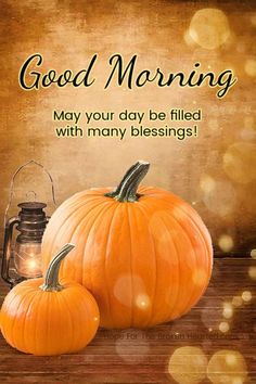 two pumpkins sitting on top of a wooden table next to a lantern with the words good morning