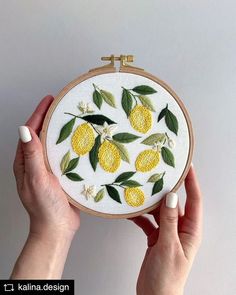 two hands holding a yellow and green embroidered lemons