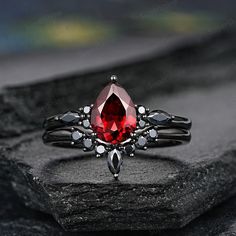 a close up of a ring with a red stone in the center on a rock