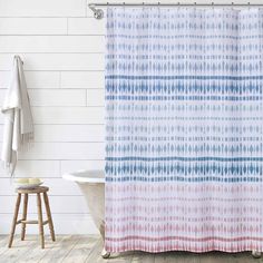 a white bath tub sitting next to a shower curtain with blue and pink designs on it