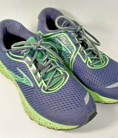 a pair of purple and green running shoes on a white surface with the shoe laces down