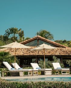 two lounge chairs and an umbrella are by the pool