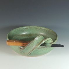 a green ceramic bowl with two wooden handles