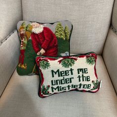 two christmas pillows sitting on top of a couch next to each other, one with a santa clause