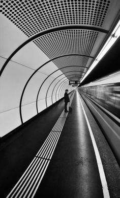 black and white photograph of a person walking in a tunnel