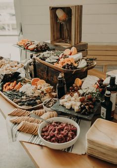 a table filled with lots of food on top of a wooden table covered in cheeses and crackers