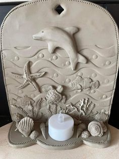 a white candle sitting on top of a table next to shells and seashells