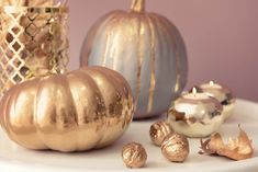 gold and silver pumpkins are on a white table with other decorative items in the background