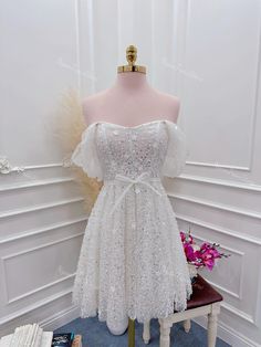 a white dress on display in front of a mannequin wearing a headpiece