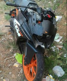 an orange and black motorcycle parked on the side of a road next to some trash