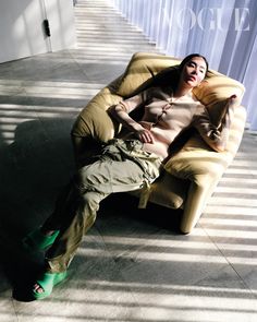 a woman sitting in a chair with her feet up on the floor next to a wall