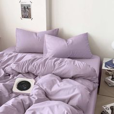 a bed covered in purple sheets and pillows