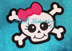 a patch with a skull and crossbones on blue glittery fabric, it has a pink heart in the middle