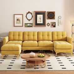 a living room with yellow couches and pictures on the wall above it, along with a coffee table