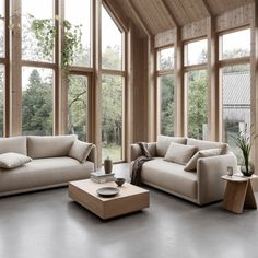 a living room filled with lots of windows next to a couch and coffee table on top of a hard wood floor