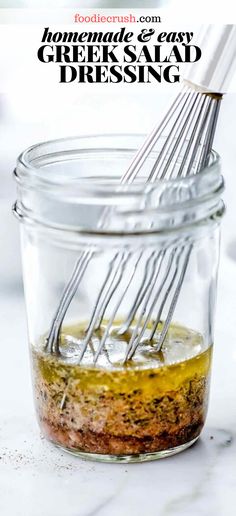 a glass jar filled with dressing and whisk on top of a white counter