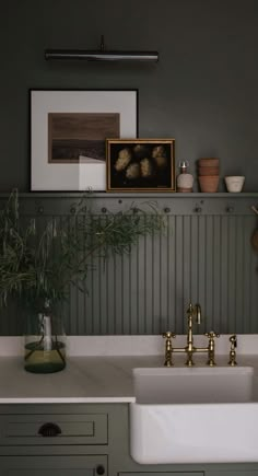 a white sink sitting under a painting on the side of a kitchen counter next to a green wall