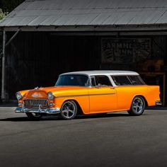 an orange and white classic car parked in front of a building with a metal roof