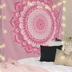 a pink wall hanging over a bed with pillows and blankets on top of the bed