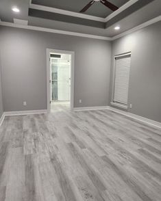 an empty room with gray walls and wood flooring is seen in this image from the inside