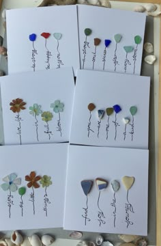 four greeting cards with flowers on them and seashells next to each other in a box