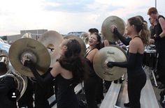 a group of women in black dresses playing musical instruments on top of a wooden platform