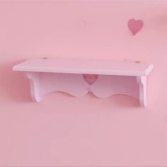 a white shelf with hearts on it against a pink wall