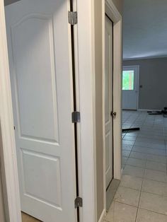 an open door leading to another room with tile flooring and white walls in the background