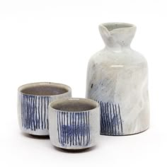 two white and blue vases sitting next to each other on a white table top