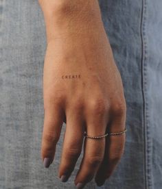 a woman's hand with the word grease written on her left wrist and an arrow tattoo