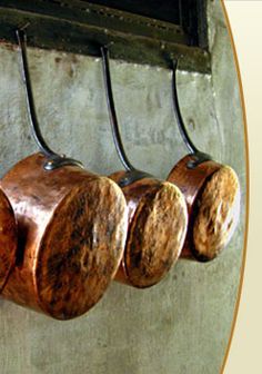 four wooden pots hanging from hooks on a wall