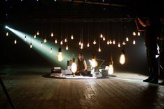 two people sitting on the floor in front of some light bulbs hanging from the ceiling