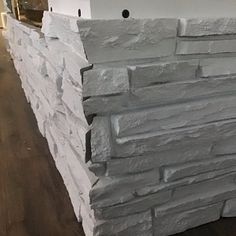 a wall made out of grey stone sitting on top of a hard wood floor