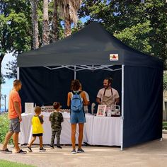 people are standing under a tent at an outdoor event