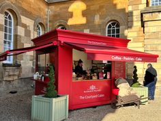 a red food cart sitting in front of a building