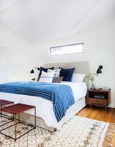 a bedroom with white walls and wood flooring has a blue blanket on the bed