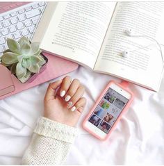 a woman laying on top of a bed next to an open book and cell phone