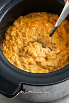 a spoon in a slow cooker filled with macaroni and cheese