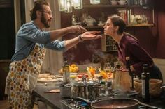 a man and woman in the kitchen preparing food for each other with utensils