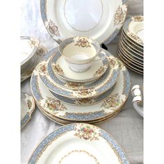 a table topped with lots of white and blue plates covered in gold trimmings