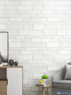 a living room with white brick wallpaper and grey couch, coffee table and sideboard