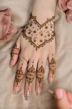 a woman's hands with hennap on top of her hand and flowers in the background