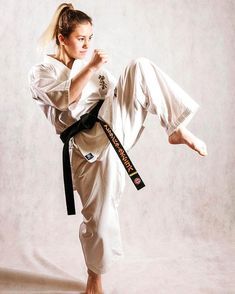 a woman is doing karate moves on a white background with one leg in the air