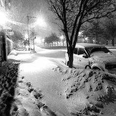 a car is parked in the snow near a tree and street light at night time