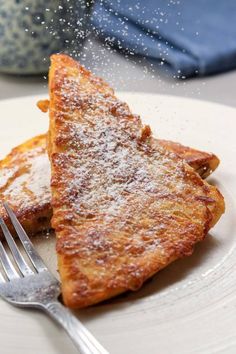 two pieces of french toast with powdered sugar on top and a fork next to it