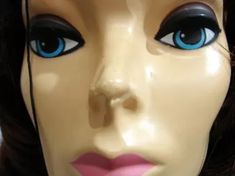 a mannequin's head with blue eyes and black hair is shown in close up